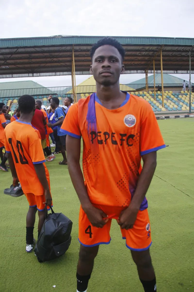 A PEPE FC player in an orange kit standing on the pitch