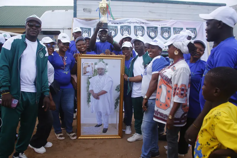 Guests and supporters gathered around a framed portrait and trophy after the match